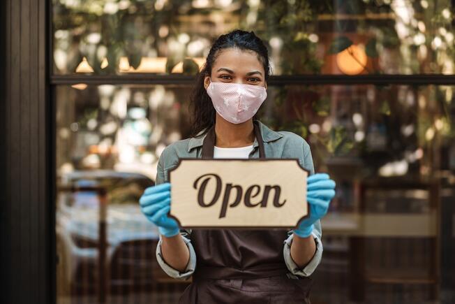 restaurant staff holding a sign open