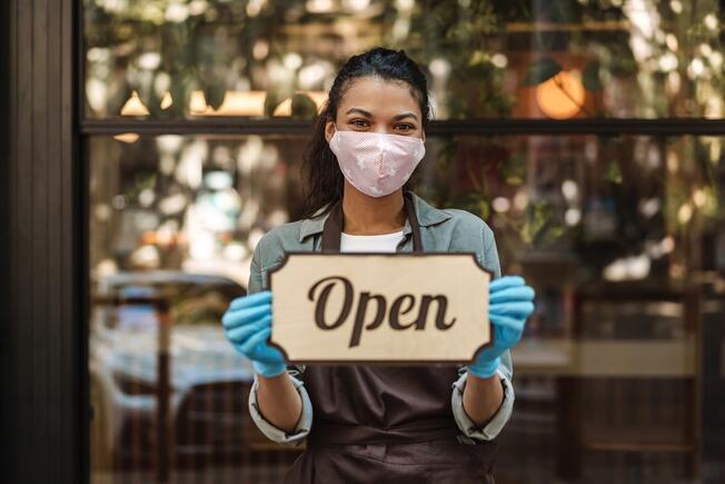 Woman coffee shop owner wearing a mask